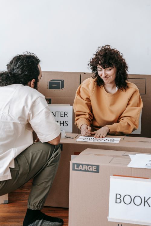 Free A couple enjoying packing boxes while preparing for a home move, highlighting teamwork and fun. Stock Photo
