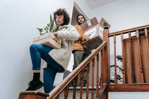 Free Couple Going Down The Stairs With Box Of Books And Plants Stock Photo