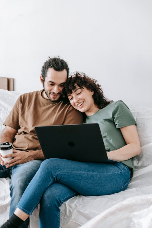 Free Couple Sitting On A Couch Looking At The Laptop Stock Photo