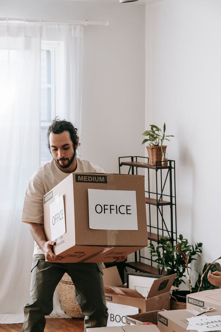 Man Carrying A Box With Office Sign