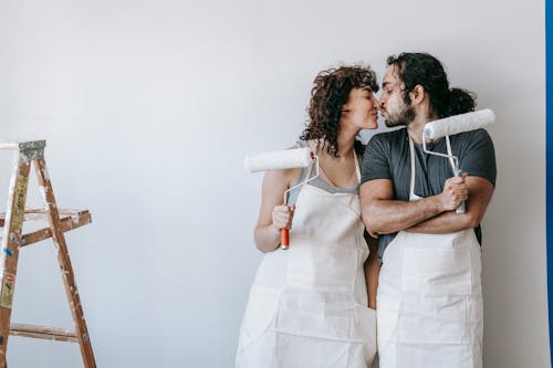 Couple Holding Paint Rollers And Kissing