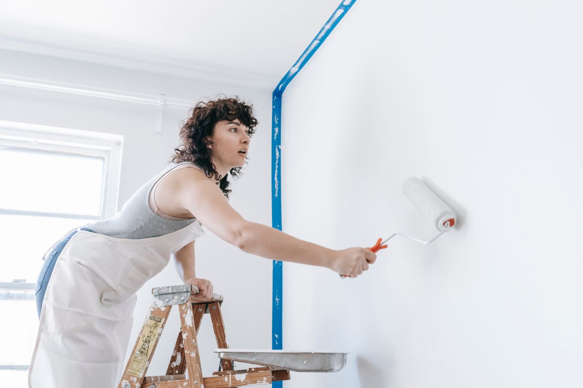 Painter rolling a fresh white finish coat on a wall