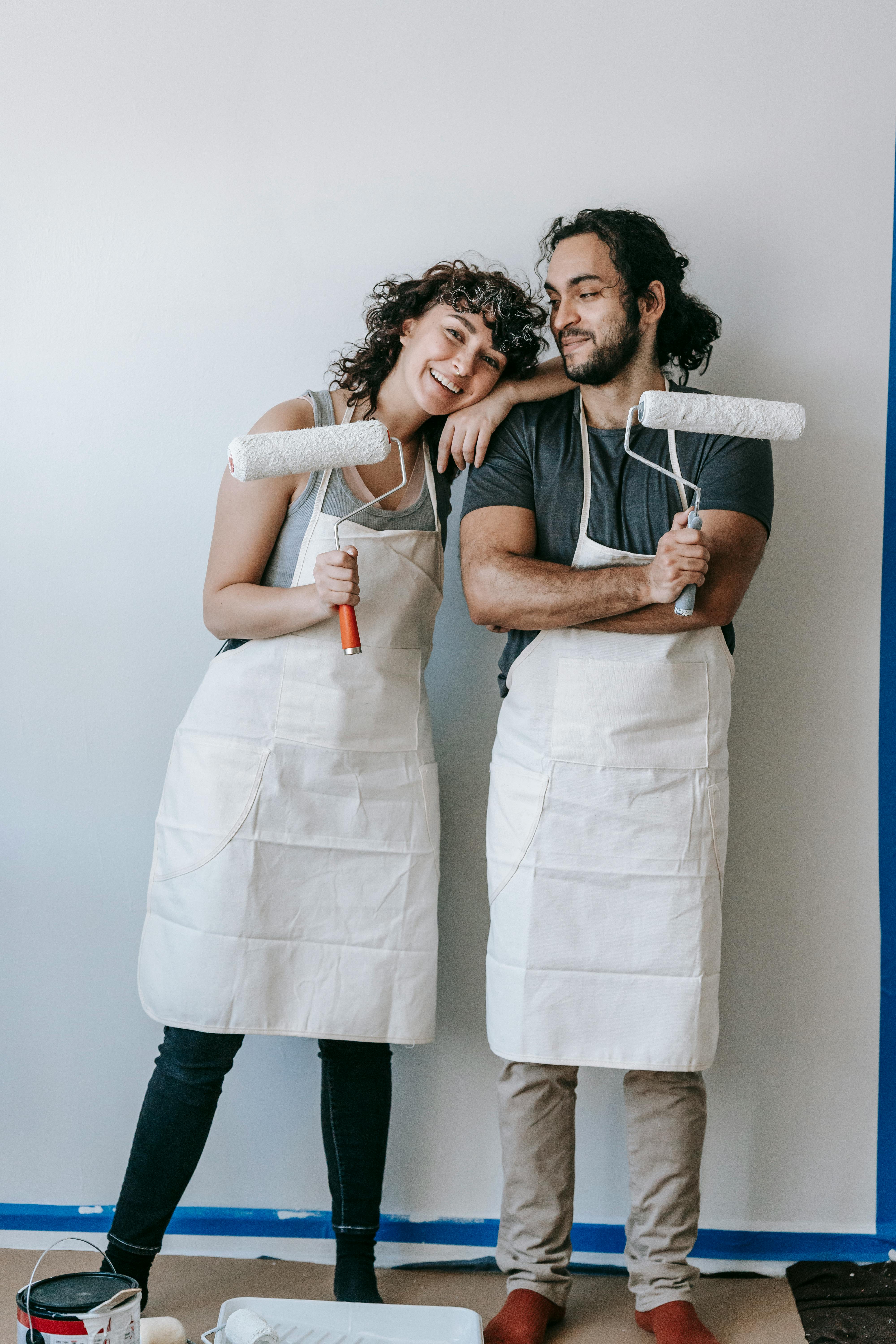 couple holding roller brushes for painting