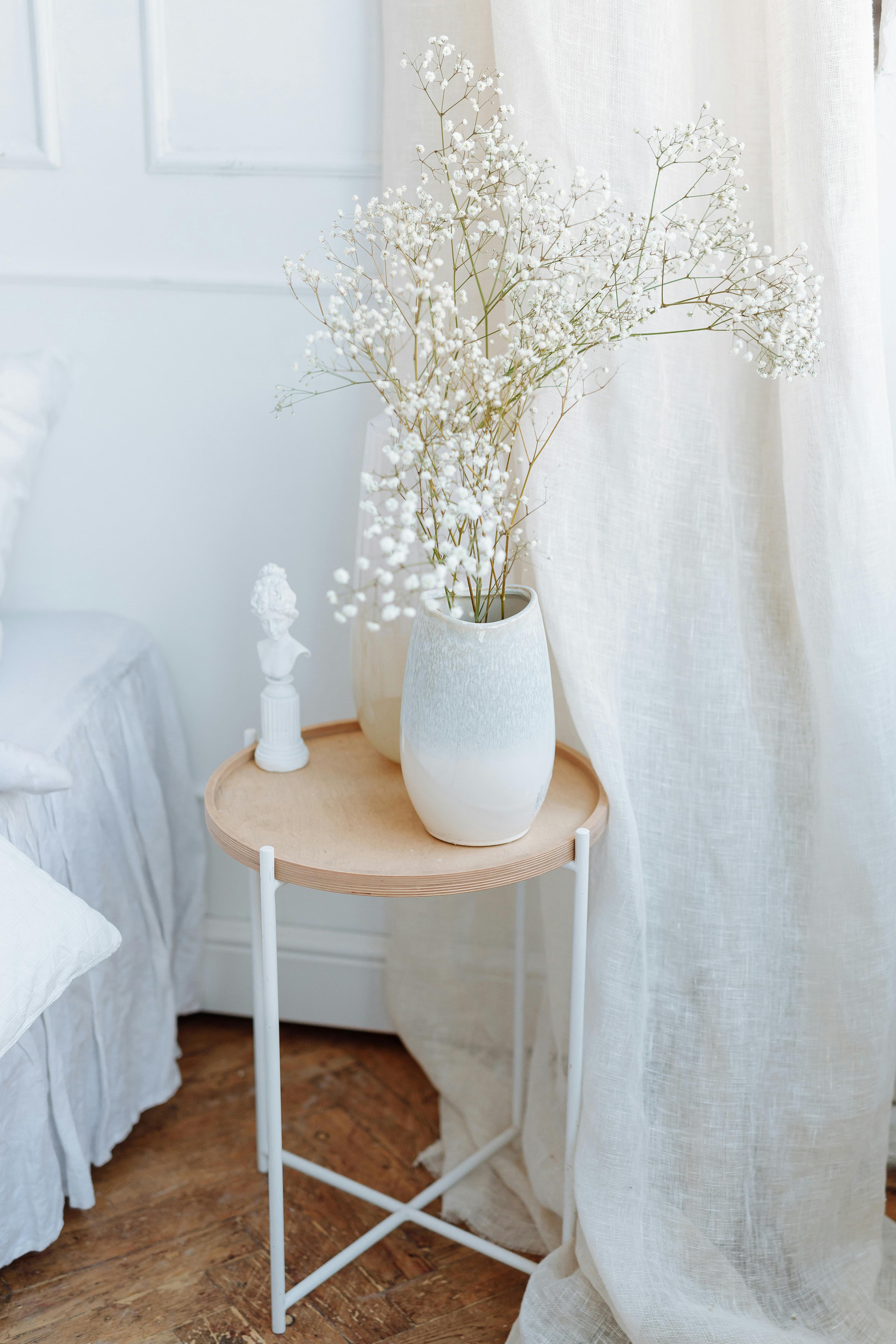 Elegant minimalist interior featuring a side table adorned with a vase of baby's breath flowers.