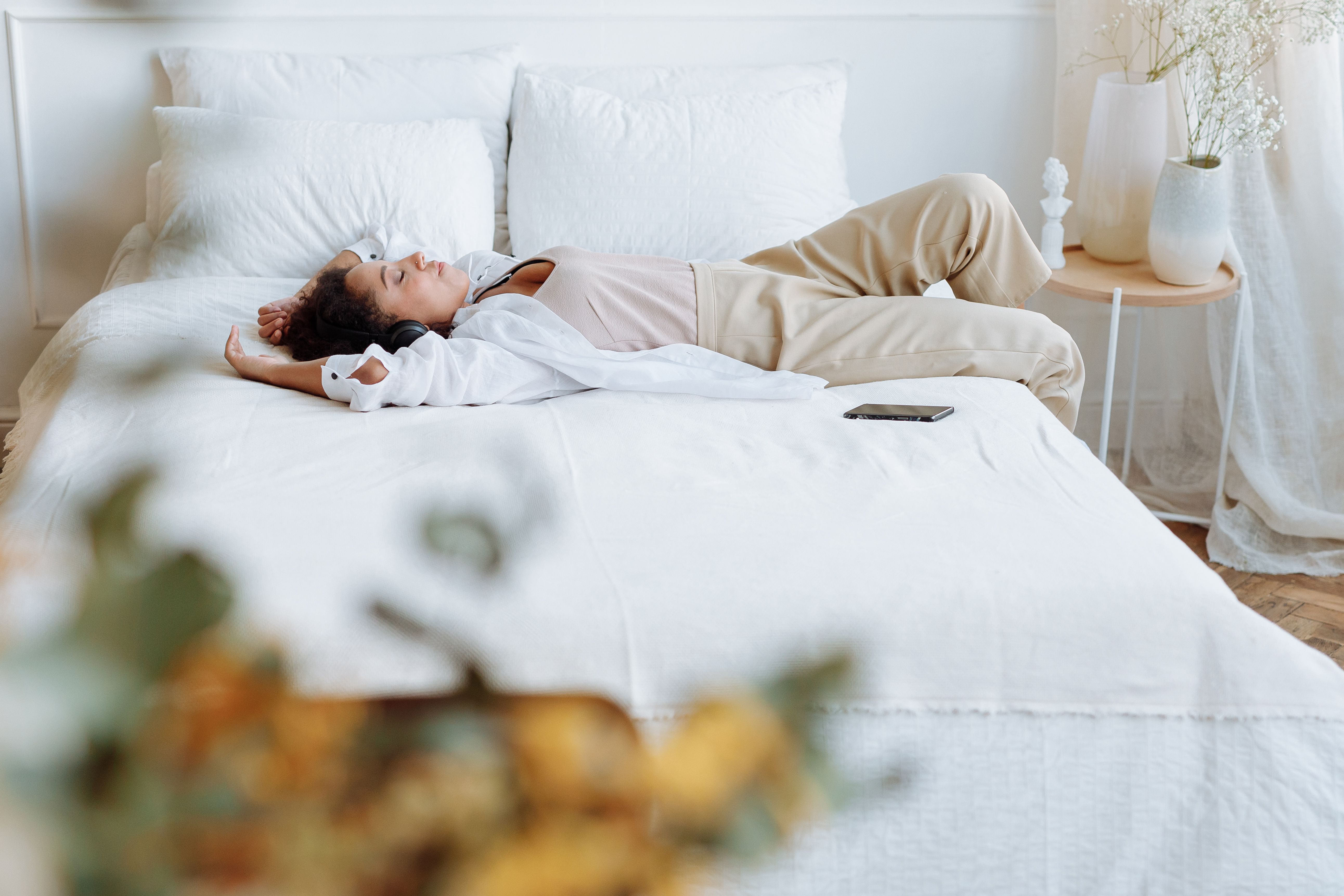 A woman enjoys a peaceful moment lying on a comfortable bed in a bright, cozy bedroom.