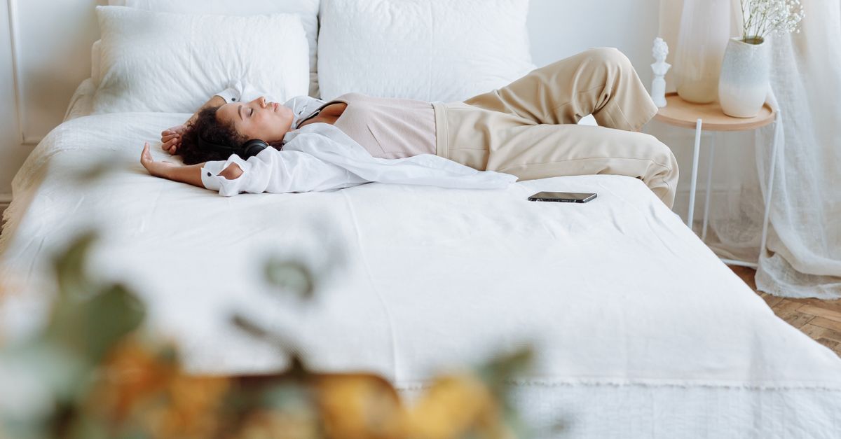 A woman enjoys a peaceful moment lying on a comfortable bed in a bright, cozy bedroom. - Evidence evidence guide for rhodiola sleep quality randomized trial