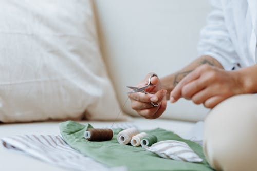 A Person Using a Scissor to Cut a Sewing Thread