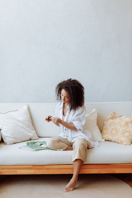 A Woman in White Long Sleeves Sitting on the Couch