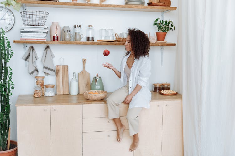 Woman With Curly Hair Tossing An Apple