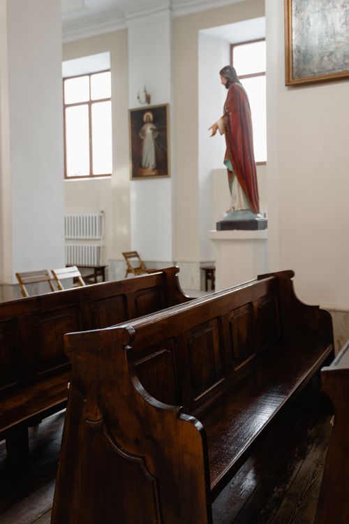 Free Serene church interior featuring elegant wooden pews and a statue, ideal for religious themes. Stock Photo