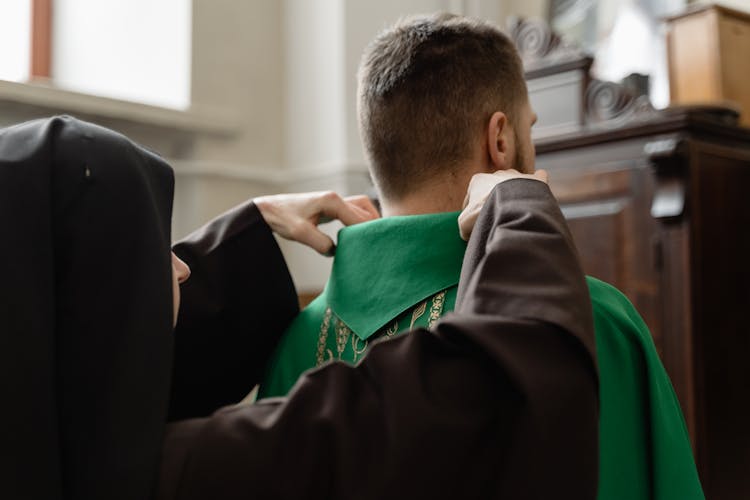 A Priest Getting Help In Fixing His Stole