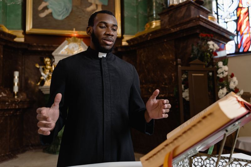A priest delivering a sermon in a beautifully decorated church interior.