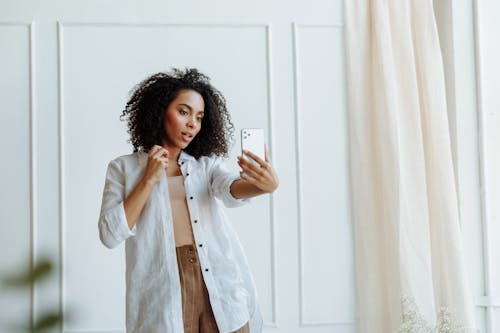 An Afro-Haired Woman Taking Selfie Using a Smartphone