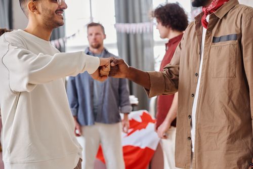 Free A group of diverse friends celebrating indoors with a cheerful fist bump during a casual party. Stock Photo