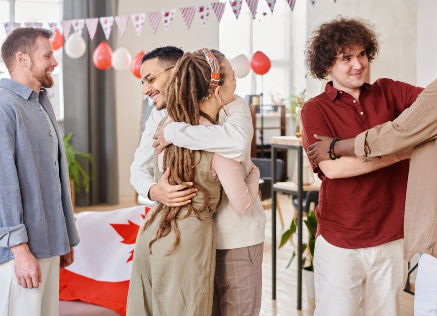 A diverse group of friends celebrating together with hugs and smiles indoors.