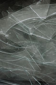 Close-up view of broken glass shards layered together, capturing reflections.