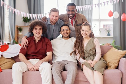 Free A cheerful and diverse group of young adults sitting together indoors, celebrating friendship. Stock Photo
