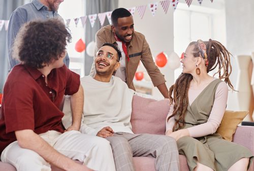 Free A joyful group of friends from diverse backgrounds socializing indoors on a cozy sofa. Stock Photo
