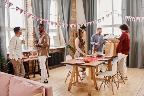 Free A diverse group of friends celebrating indoors with festive decorations and a table set for dining. Stock Photo