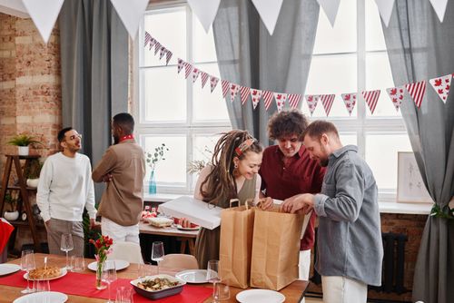 Free A joyful group of friends celebrates Canada Day indoors with festive decor and delicious food. Stock Photo