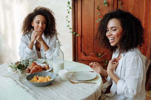 Free Two young women enjoying a relaxed breakfast together at home. A moment of laughter and connection. Stock Photo