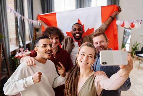 Free A diverse group of friends celebrating Canada Day with a joyful selfie indoors. Stock Photo