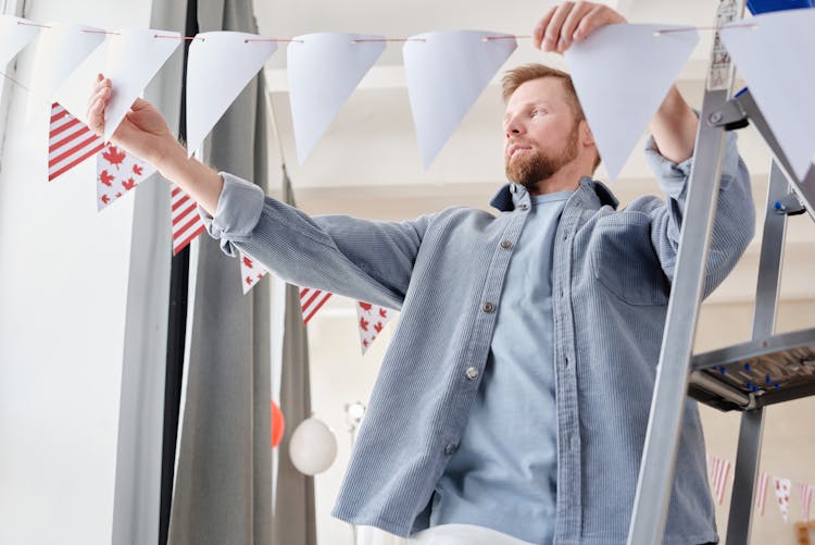 A Man Hanging A Party Banner