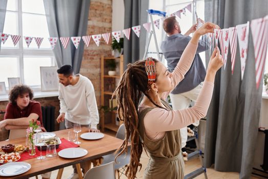 Friends decorating a room with Canada Day banners, setting a festive indoor atmosphere.