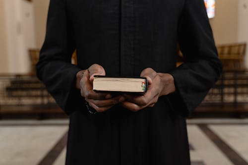 Free A Person in Black Long Sleeve Holding a Bible Stock Photo