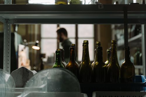 Free Dark and atmospheric indoor setting with glass bottles and a blurred figure. Stock Photo