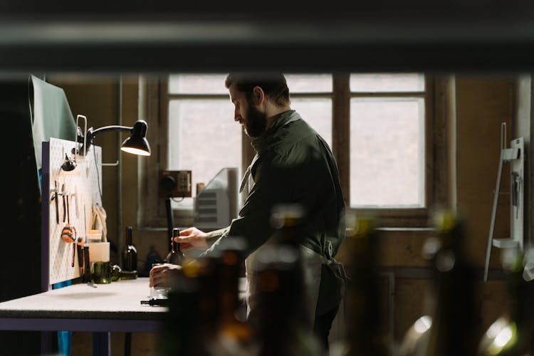 A Man Holding A Glass Bottle