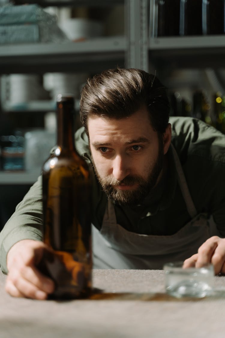 A Man Holding A Glass Bottle