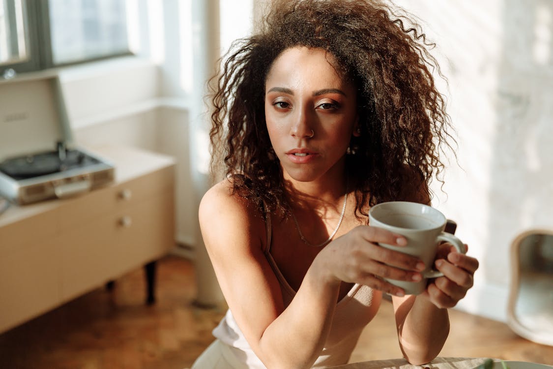Woman with Curly Hair Holding Coffee Cup