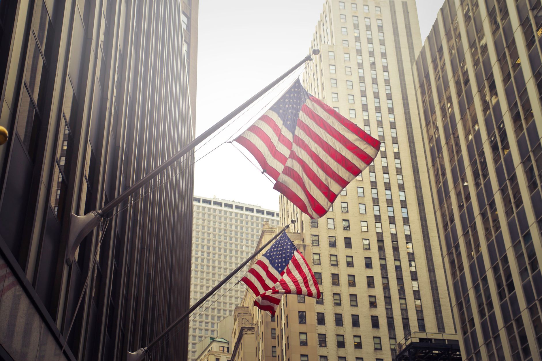 American flags waving among New York skyscrapers, showcasing urban patriotism.