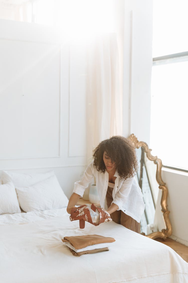 Woman With Curly Hair Preparing Her Clothes On A Bed