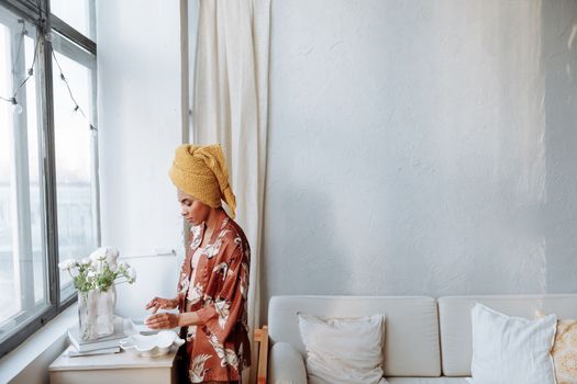Serene woman in a kimono stands by a window, enjoying a calm morning at home.