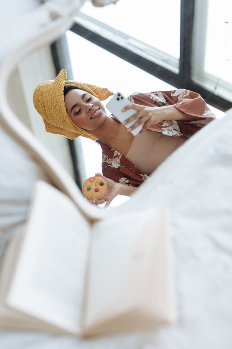 A Woman Holding A Cookie While Using Her Phone