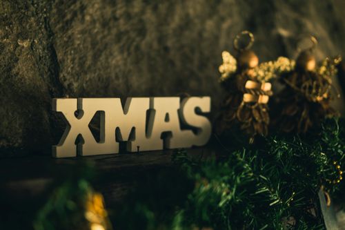 Free Close-up of festive Christmas decorations featuring a 'XMAS' sign and gold ornaments. Stock Photo