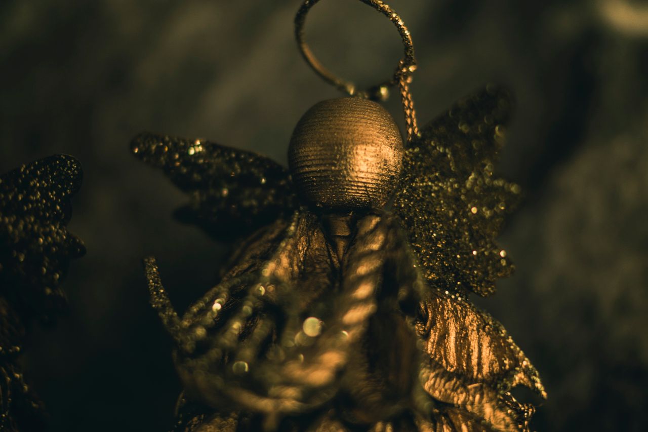 a close up view of a shimmering gold angel ornament with glittery wing