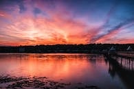 一座风景秀丽的桥梁旁，平静的河水倒映着令人惊叹的日落天空