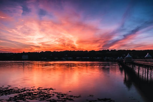 一座风景秀丽的桥梁旁，平静的河水倒映着令人惊叹的日落天空