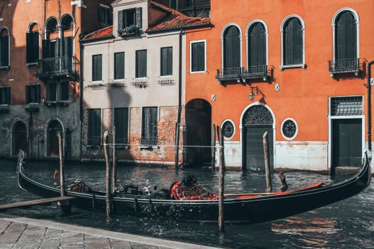 Gondola on canal against aged masonry houses in city