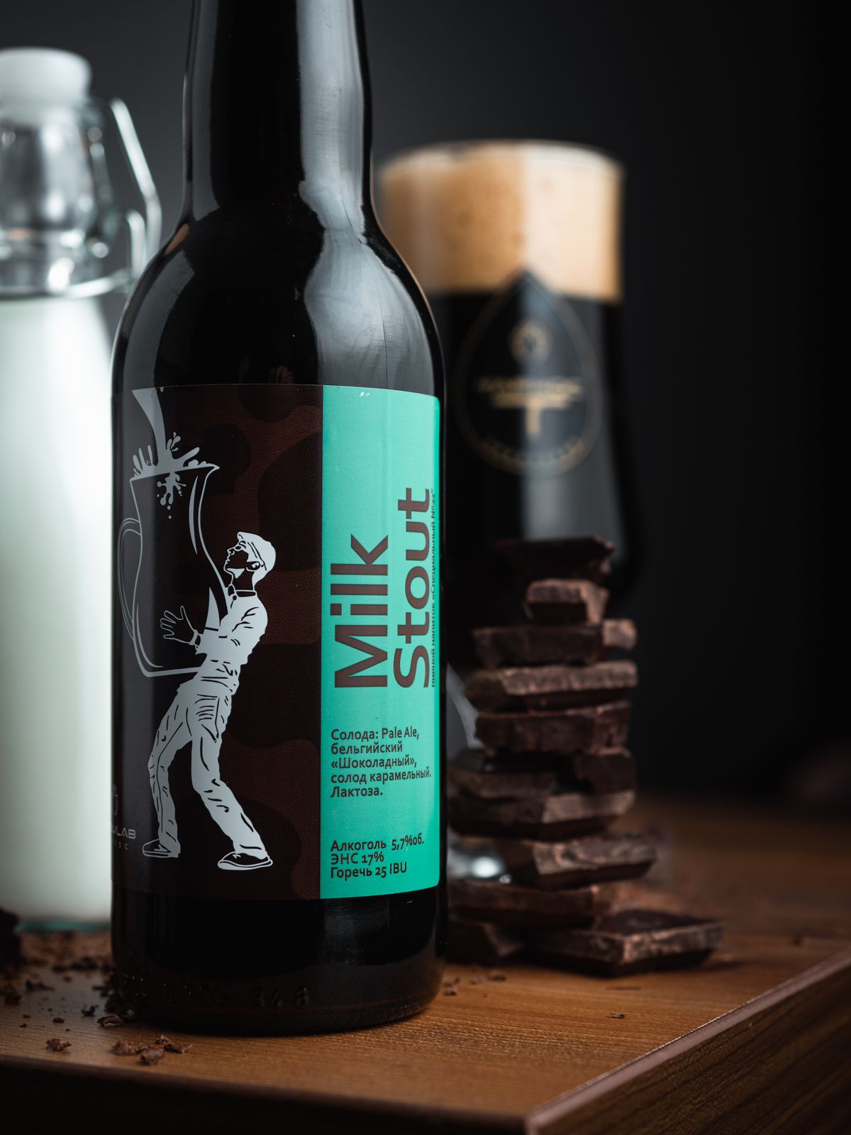 Milk stout bottle with turquoise label beside dark chocolate and a poured glass
