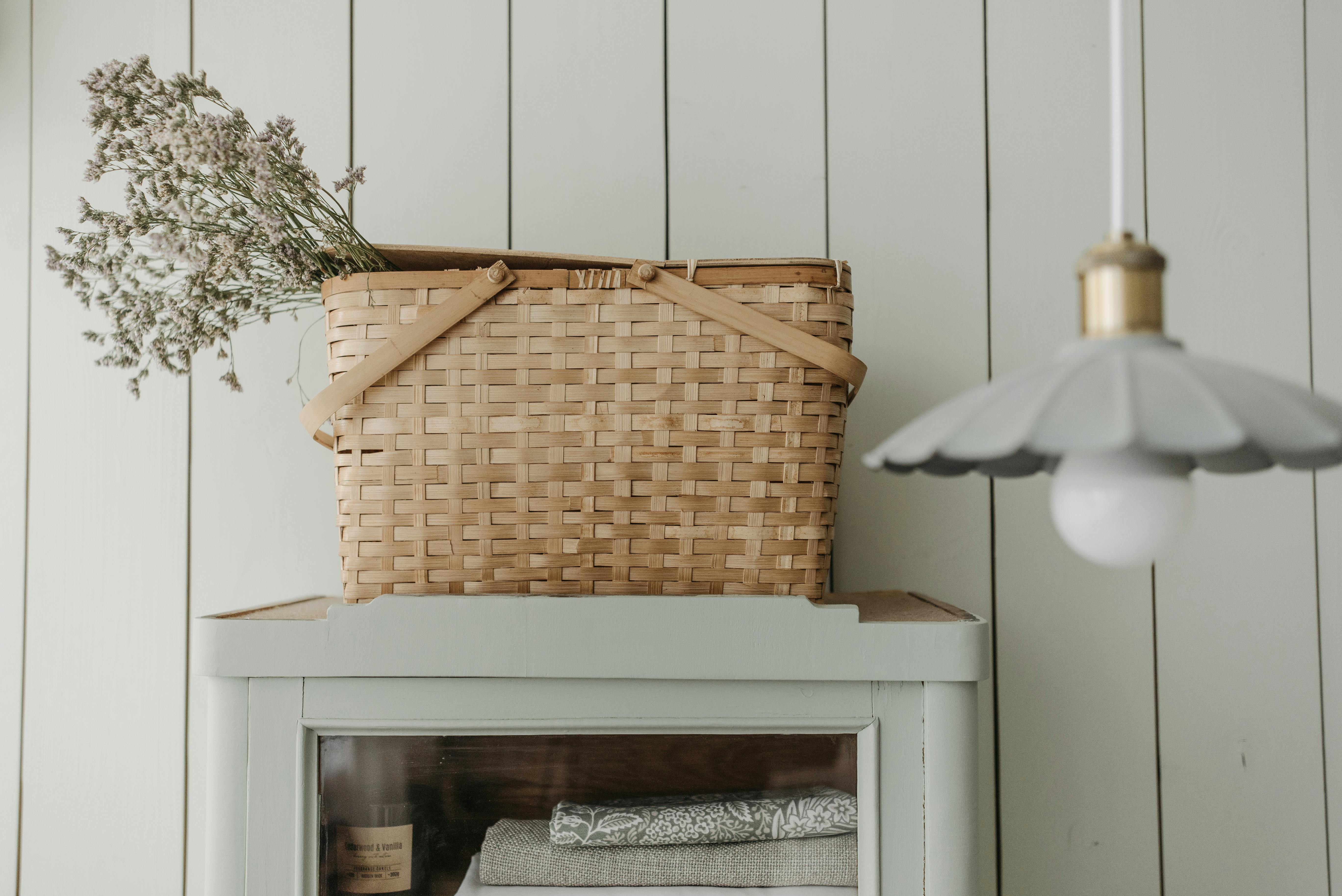 A woven basket with flowers atop a vintage cabinet in a cozy interior setting.