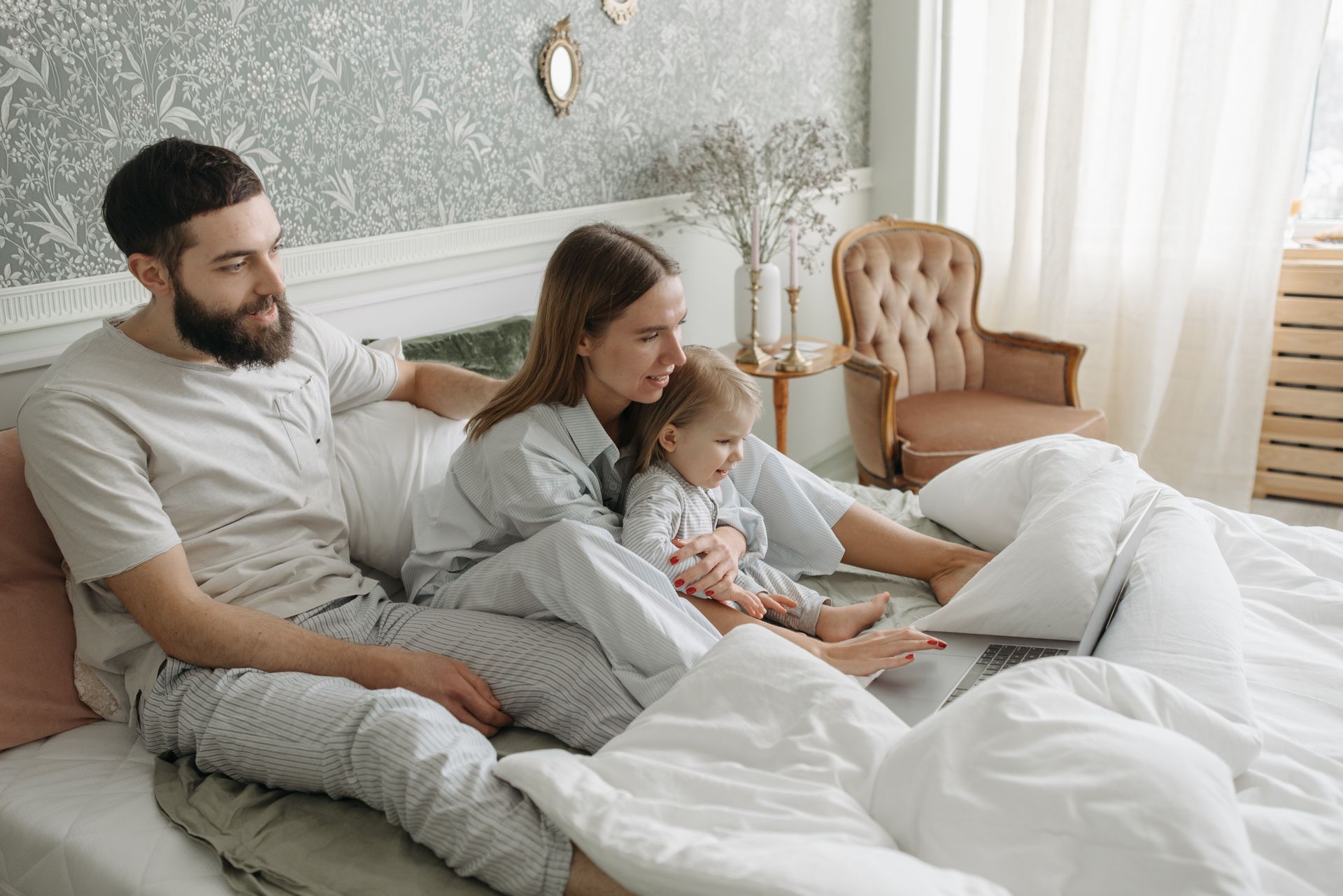 Family spending quality time together in the bedroom, watching on a laptop.