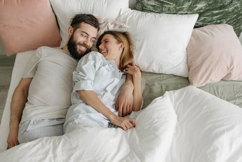 Free Overhead Shot of a Couple Smiling on a Bed Stock Photo