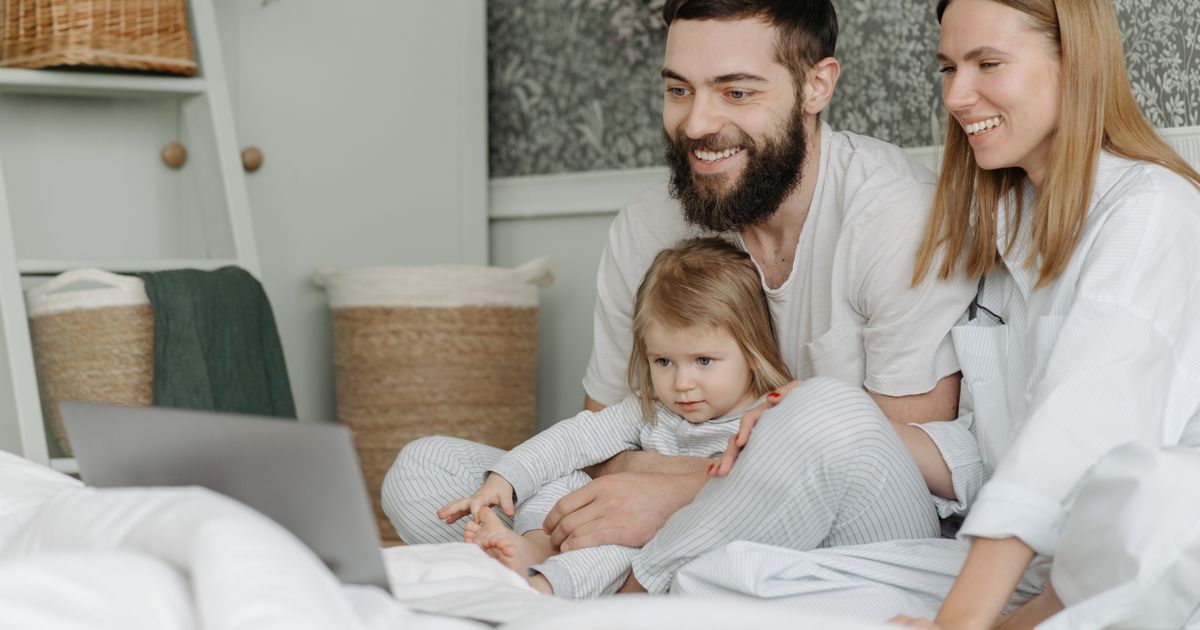 Família de três aproveitando o tempo de união assistindo a um laptop juntos em casa.