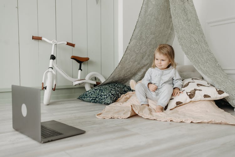 A Child Watching On A Laptop While Sitting