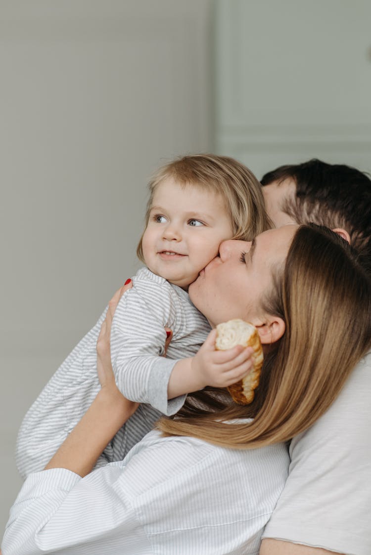 A Mother Kissing Her Daughter On The Cheek