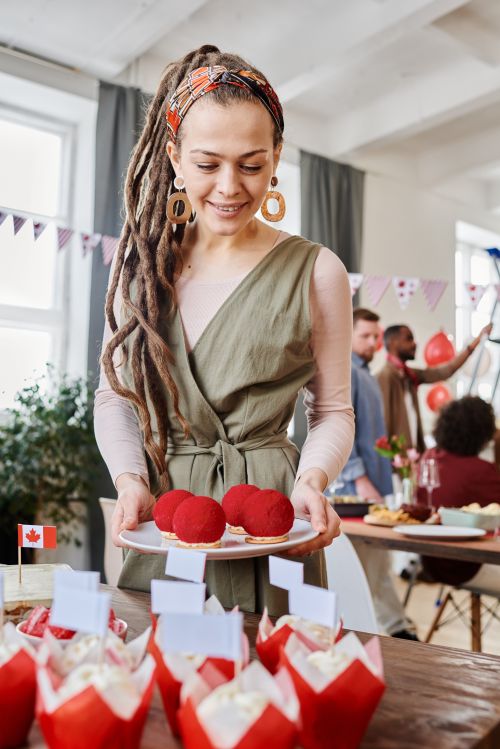 Free Smiling woman serving red desserts at a festive indoor party. Stock Photo